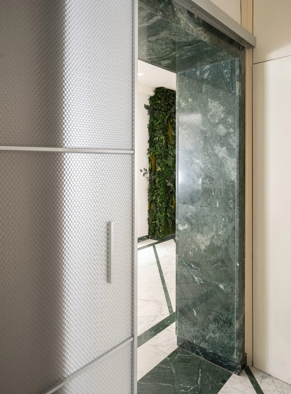 Fos 90 wall mounted sliding door in a marble clad opening, a figure visible through the panel