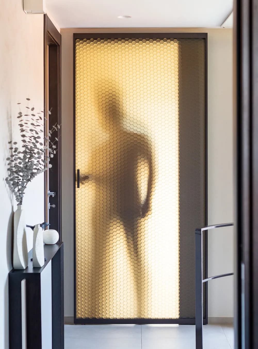 Fos wall sliding door with a hidden track, a person silhouetted behind the backlit panel