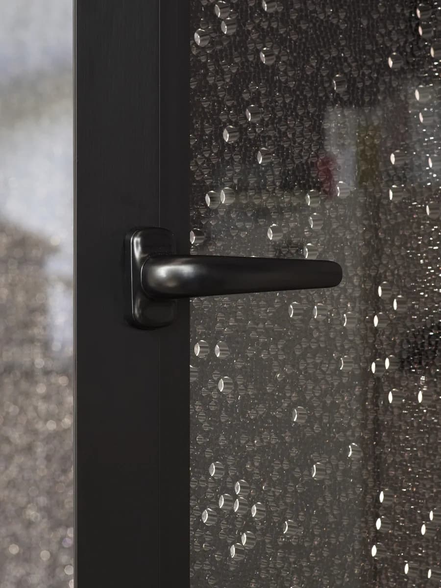 Black lever handle on a Koros door with a dark bubble patterned panel