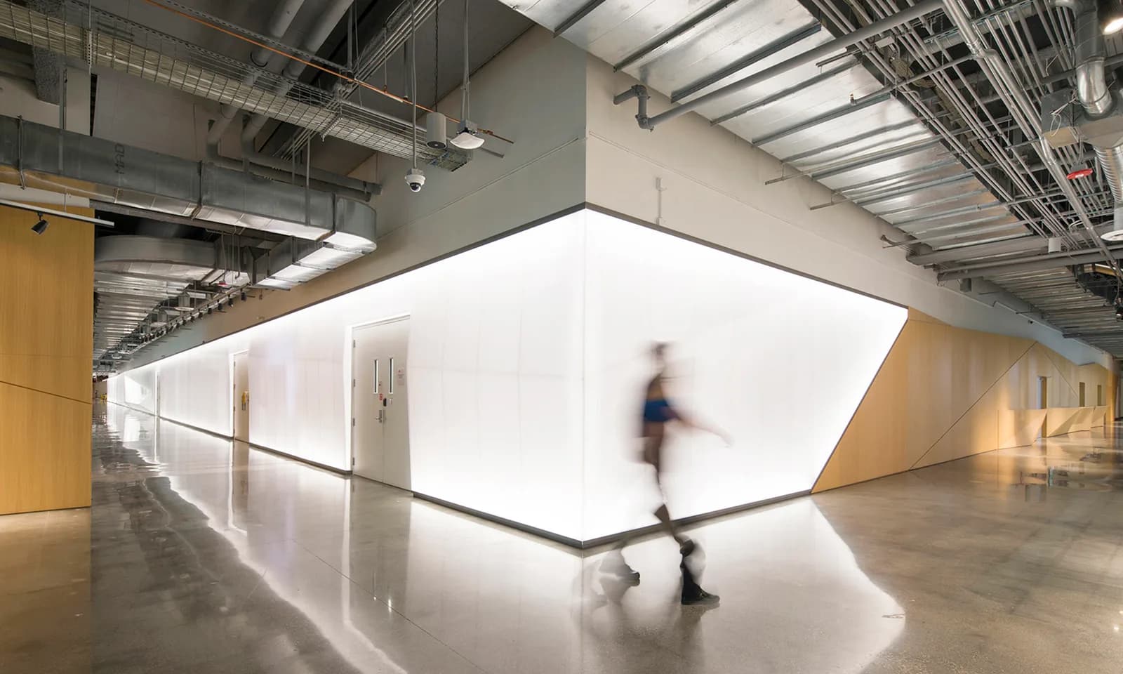 Backlit white panel wall wrapping an office corridor