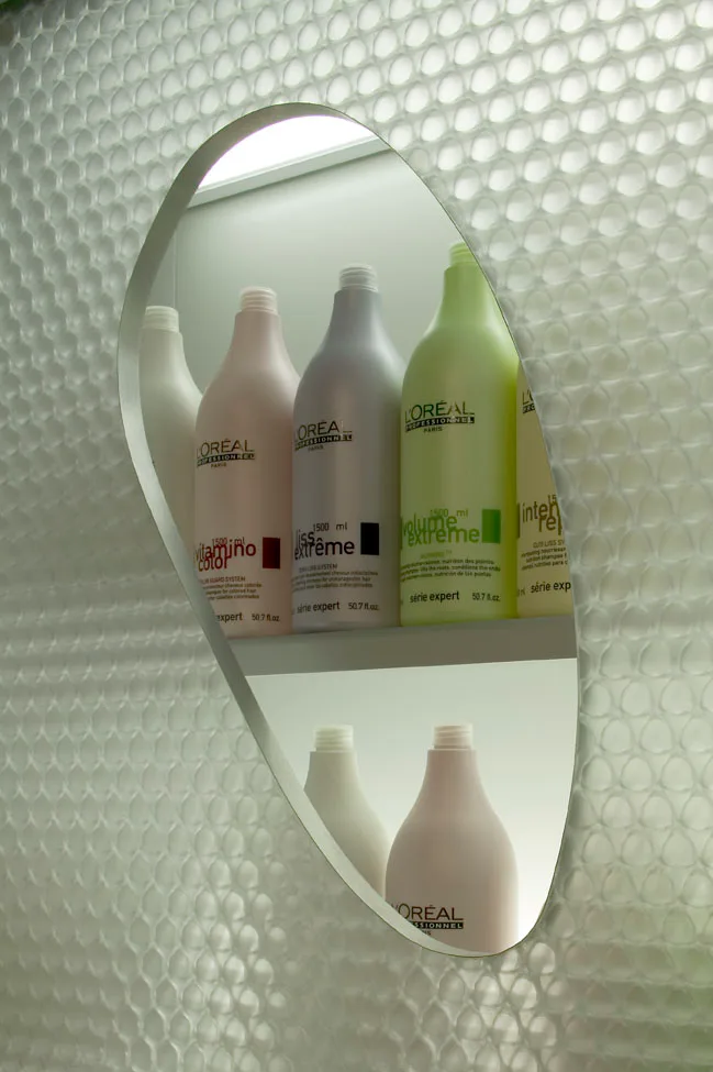 Mirror panel with a cut out mirror shape in front of a salon shelf