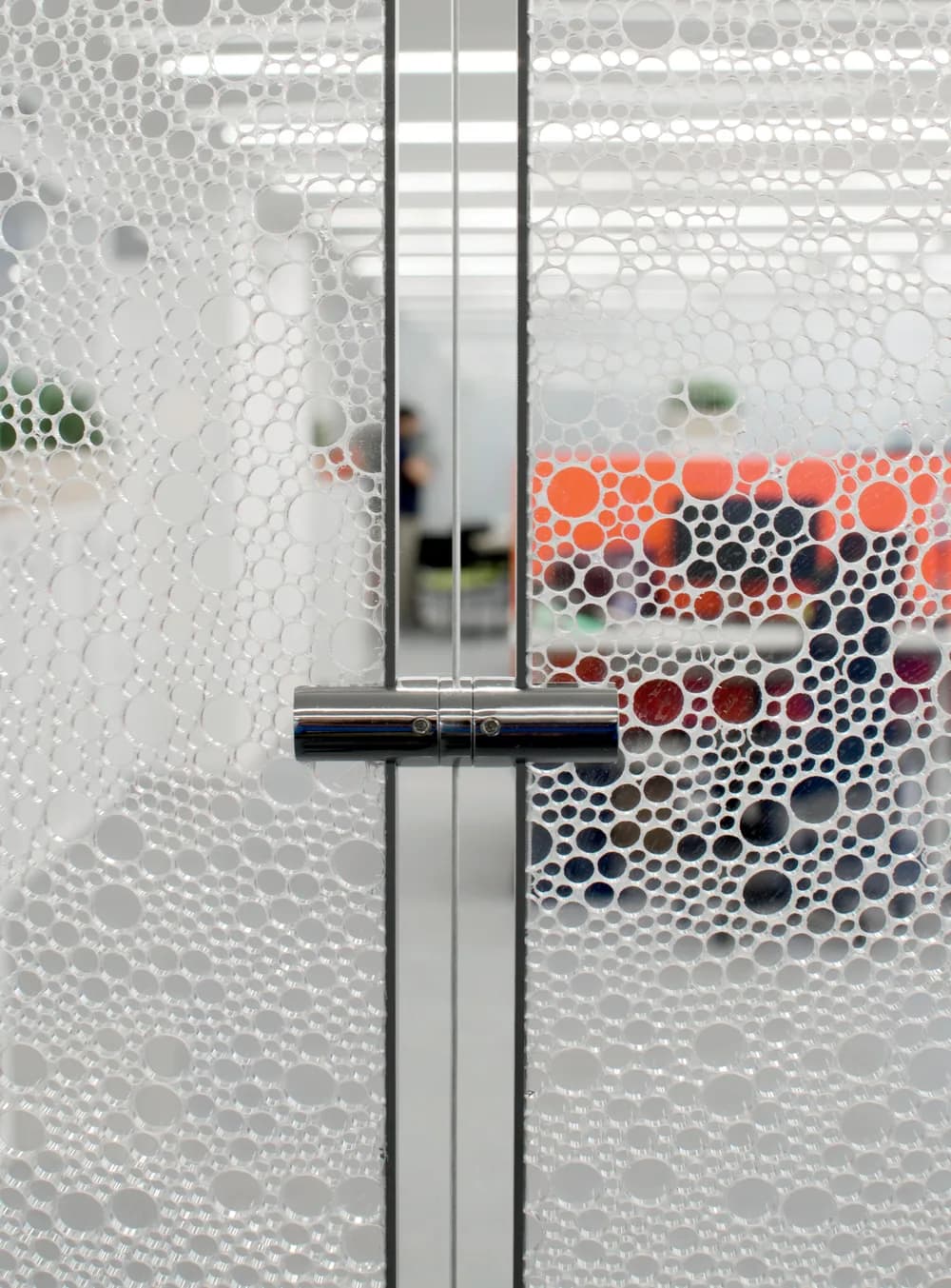 Polished steel clamp joining two Stretch panels, an office in colour behind the honeycomb