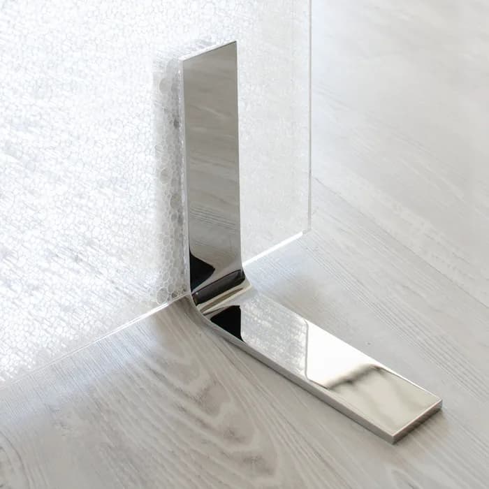 Upset Design foot in mirror polished steel clamping a satin panel
