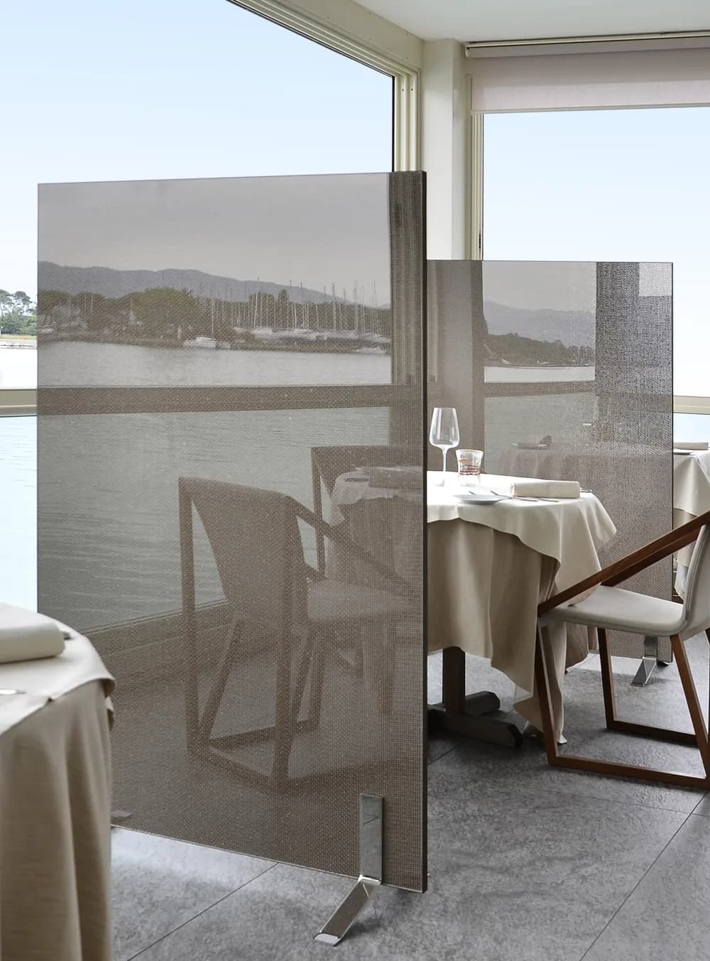 Upset partition in a bronze panel dividing restaurant tables by a window over the water