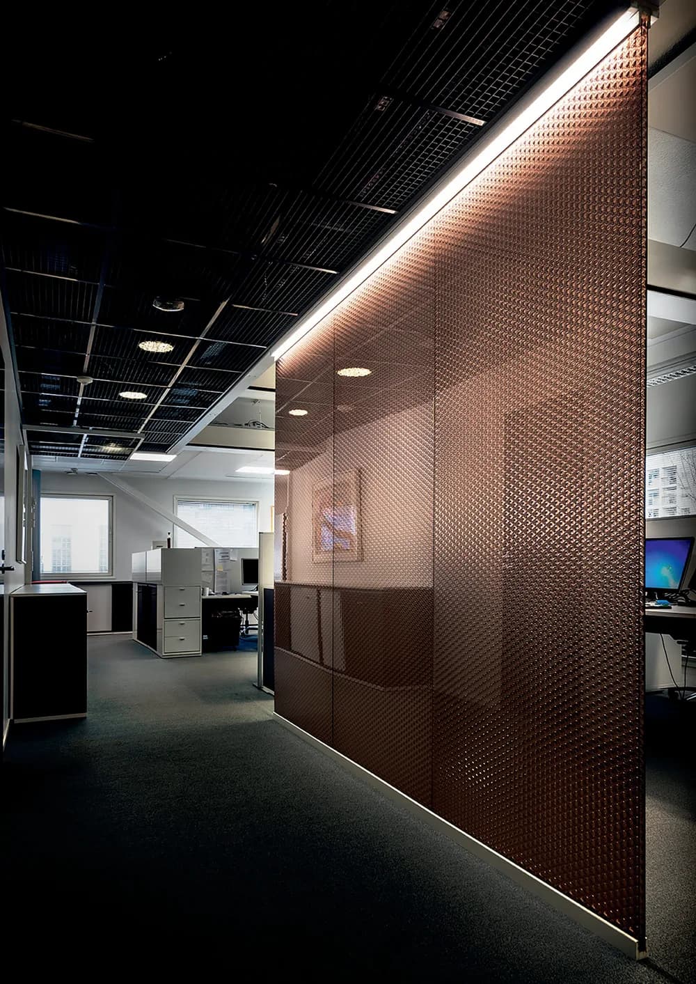 Wallite full height partition wall in copper toned honeycomb panels along an office with a light strip above